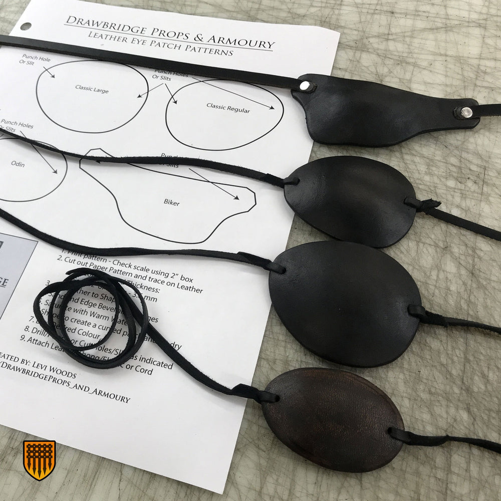 Four different black eye patches with leather thonging siting on a paper pattern from Drawbridge Props and Armoury.
