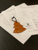 Brown leather Christmas tree ornament with rivets sitting on  paper patterns of Christmas ornaments from Drawbridge Props and Armoury.