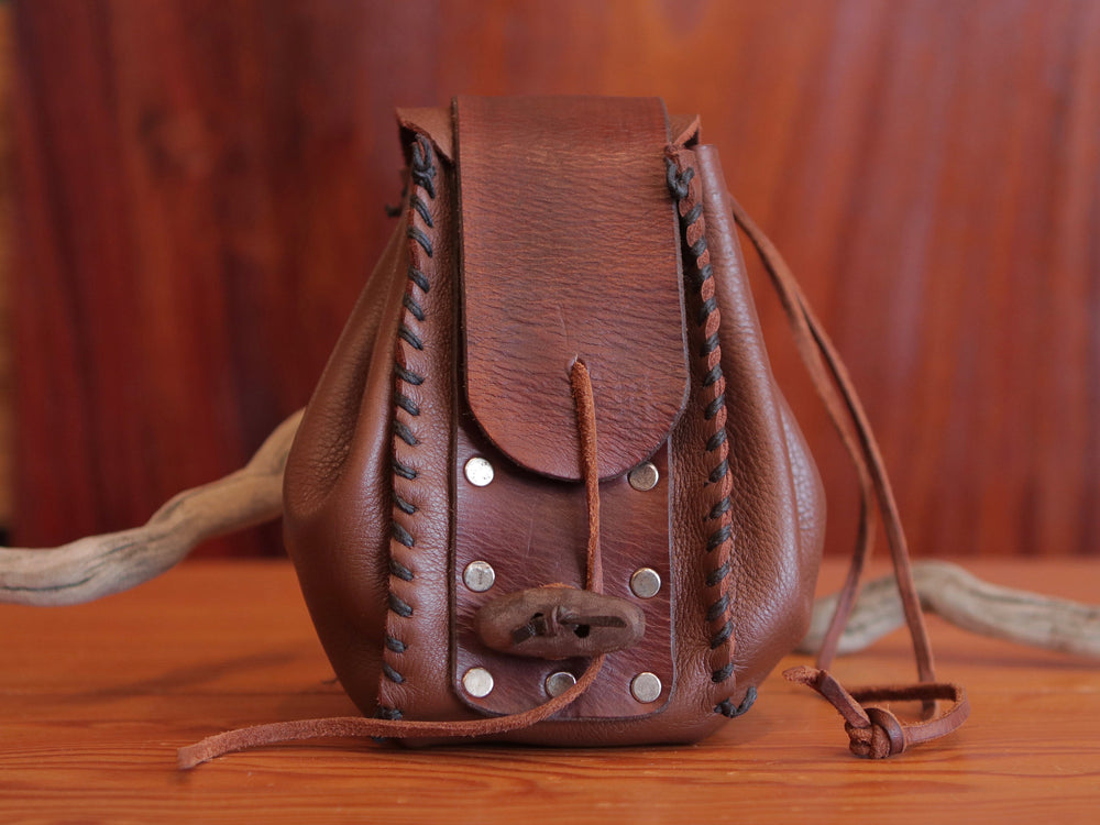 Brown leather handmade pouch with contrasting dark brown stitching, flat rivets, leather drawstring and rustic toggle to close at front.